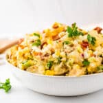 Bacon Potato salad in a white serving bowl with parsley garnish.