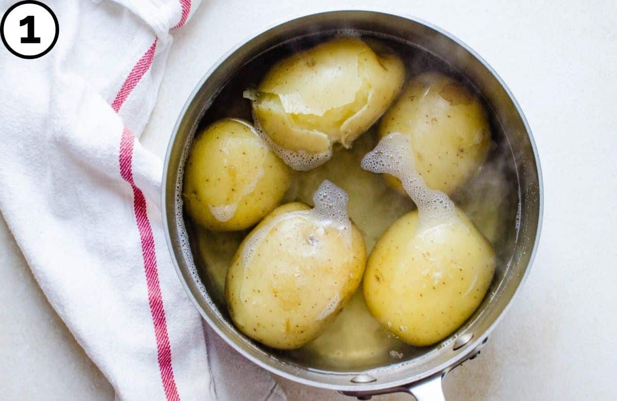 Boiled whole potatoes in a saucepan.