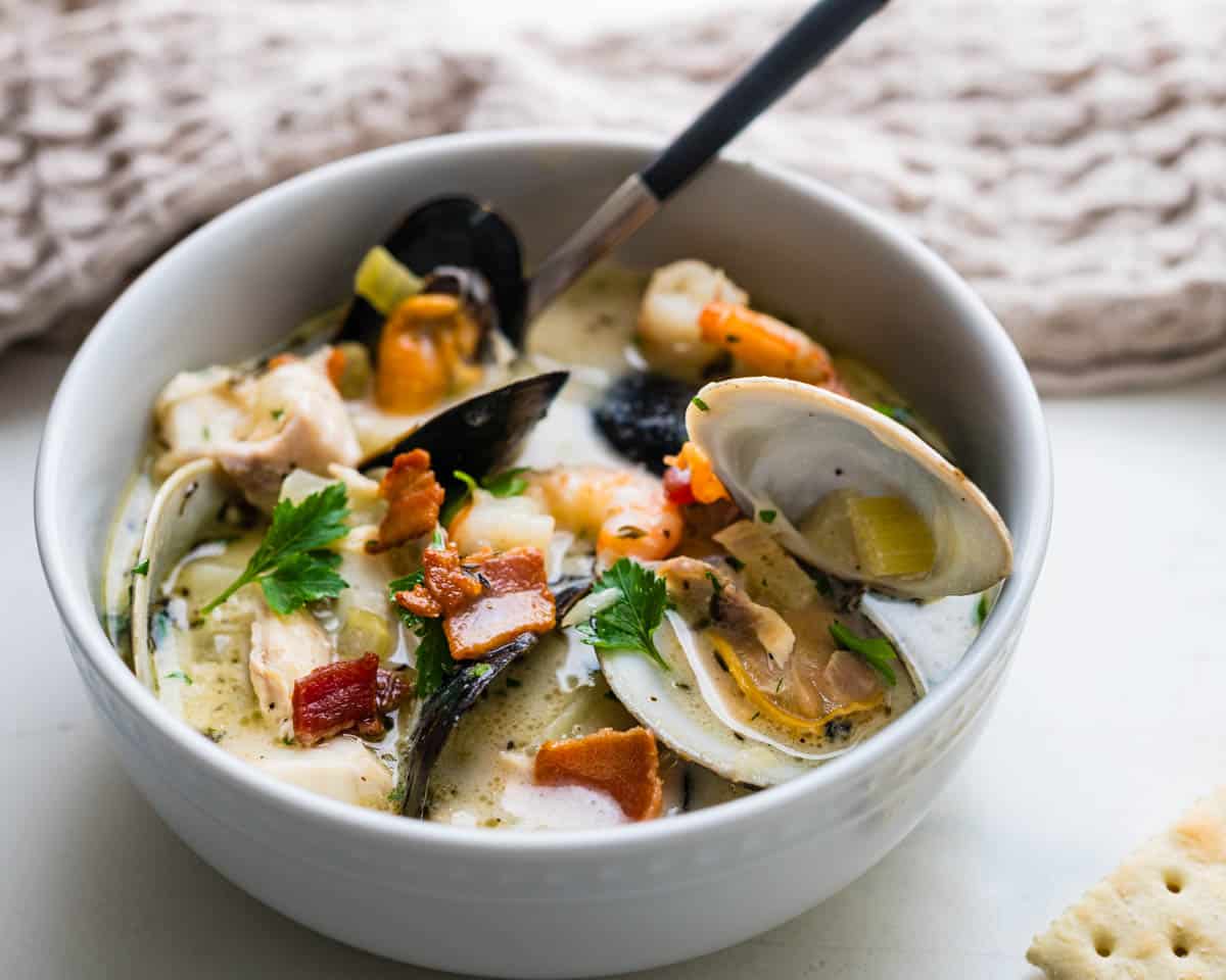 Serving a bowl of the seafood chowder with bacon on top.
