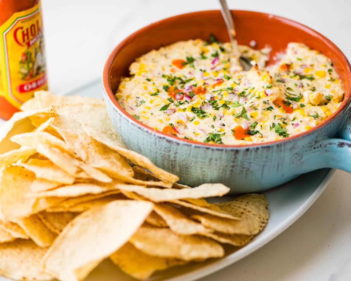 Mexican Street Corn Dip with tortilla chips and hot sauce.