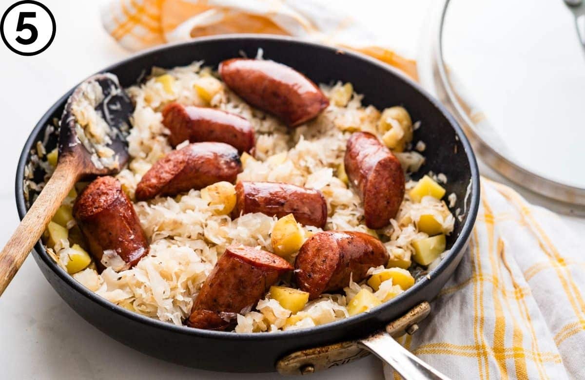 Finished kielbasa and sauerkraut skillet dinner simmering under a lid.