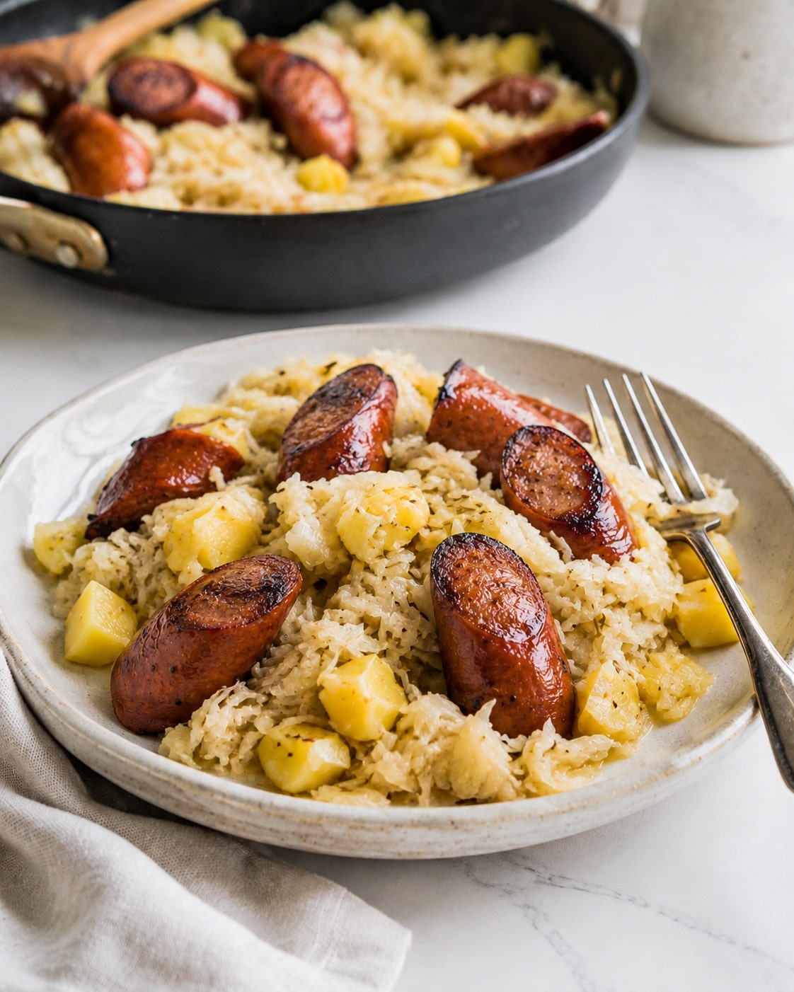 A closeup of the Polish sausage and sauerkraut on a stoneware plate.