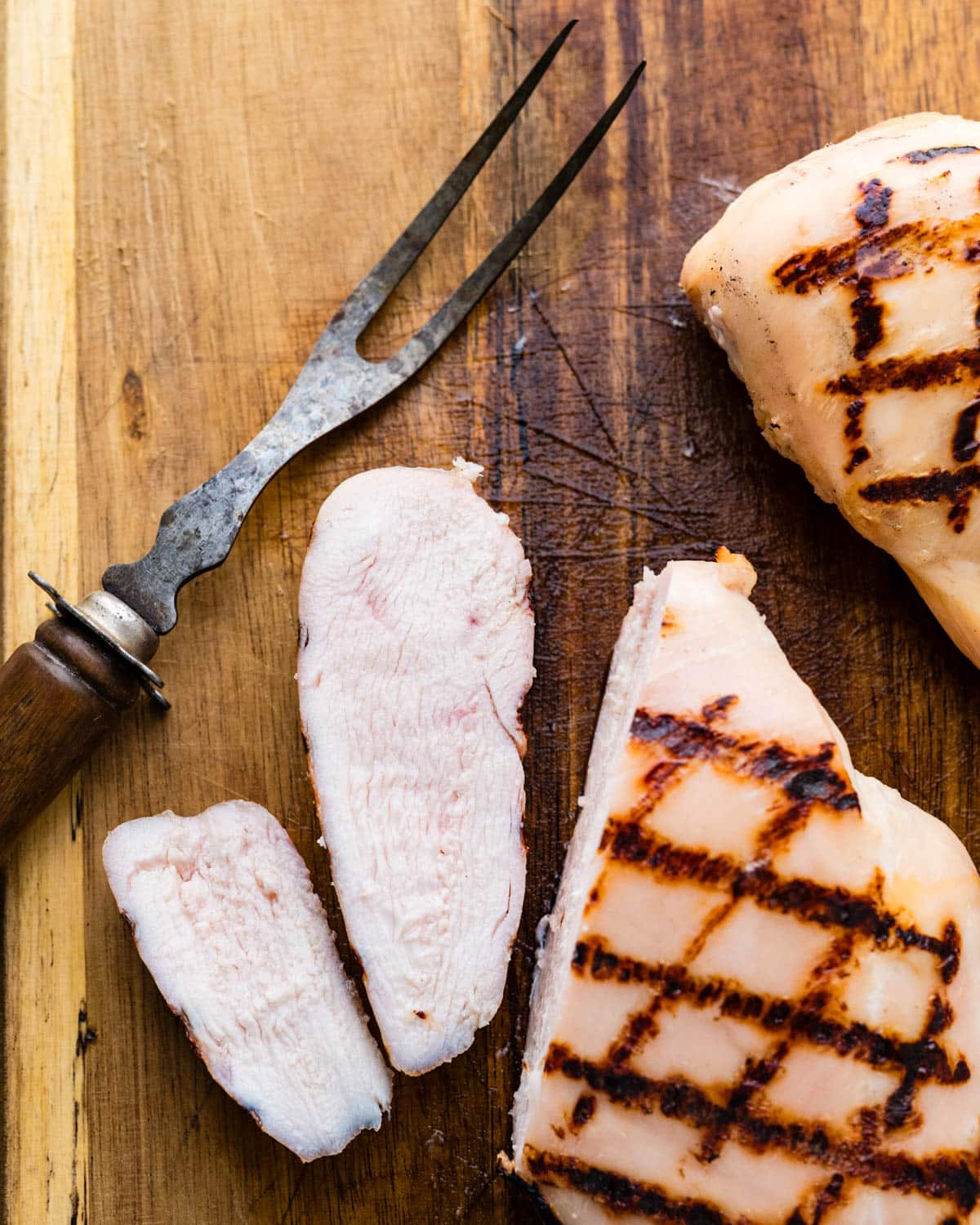 An overhead shot of the brined chicken breasts being sliced to show the moist interior.