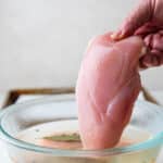 Pulling a chicken breast from the brine.