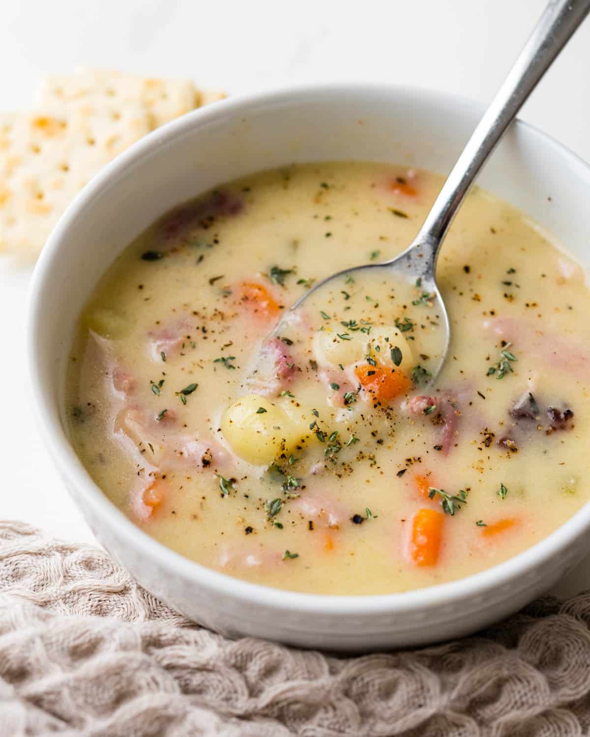 A garnished bowl of ham and potato soup