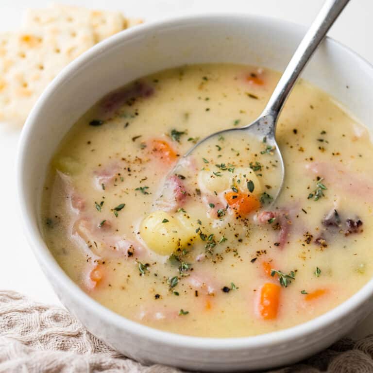 A bowl of ham and potato soup with pepper and thyme.